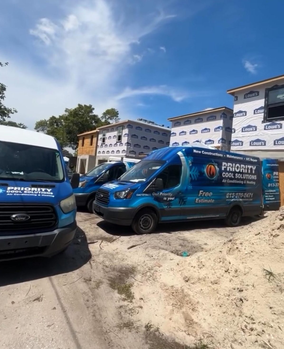 Priority Cool Solutions vans at a construction site under a clear blue sky.