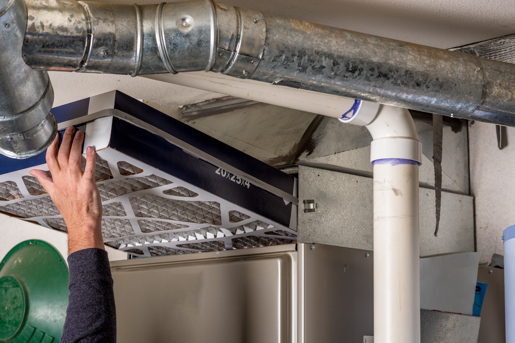 Person replacing an air filter in a furnace system.