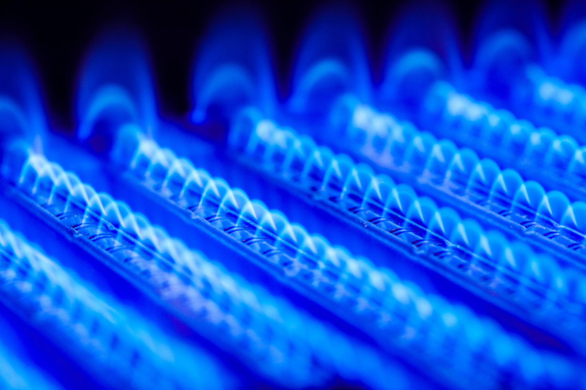 Close-up of a vibrant blue gas flame pattern on a burner, emitting a bright and consistent glow.