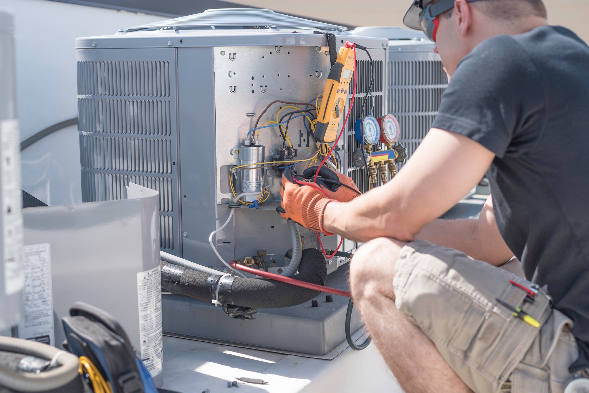 Technician repairing an air conditioning unit on a rooftop.