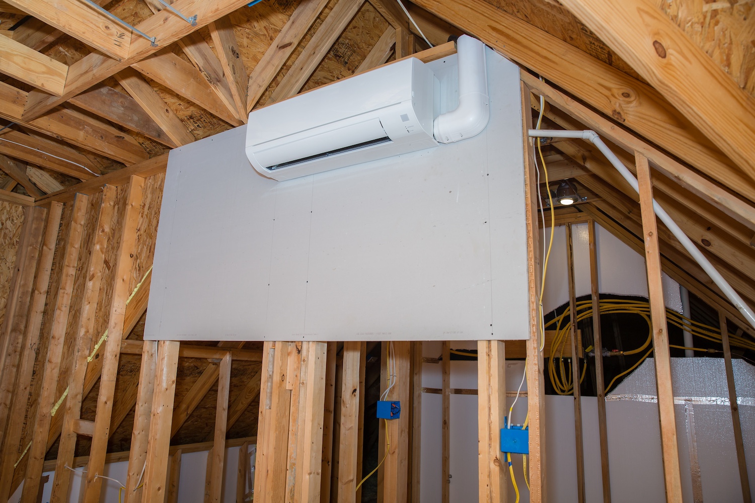 Attic space with wooden framing and installed air conditioning unit.