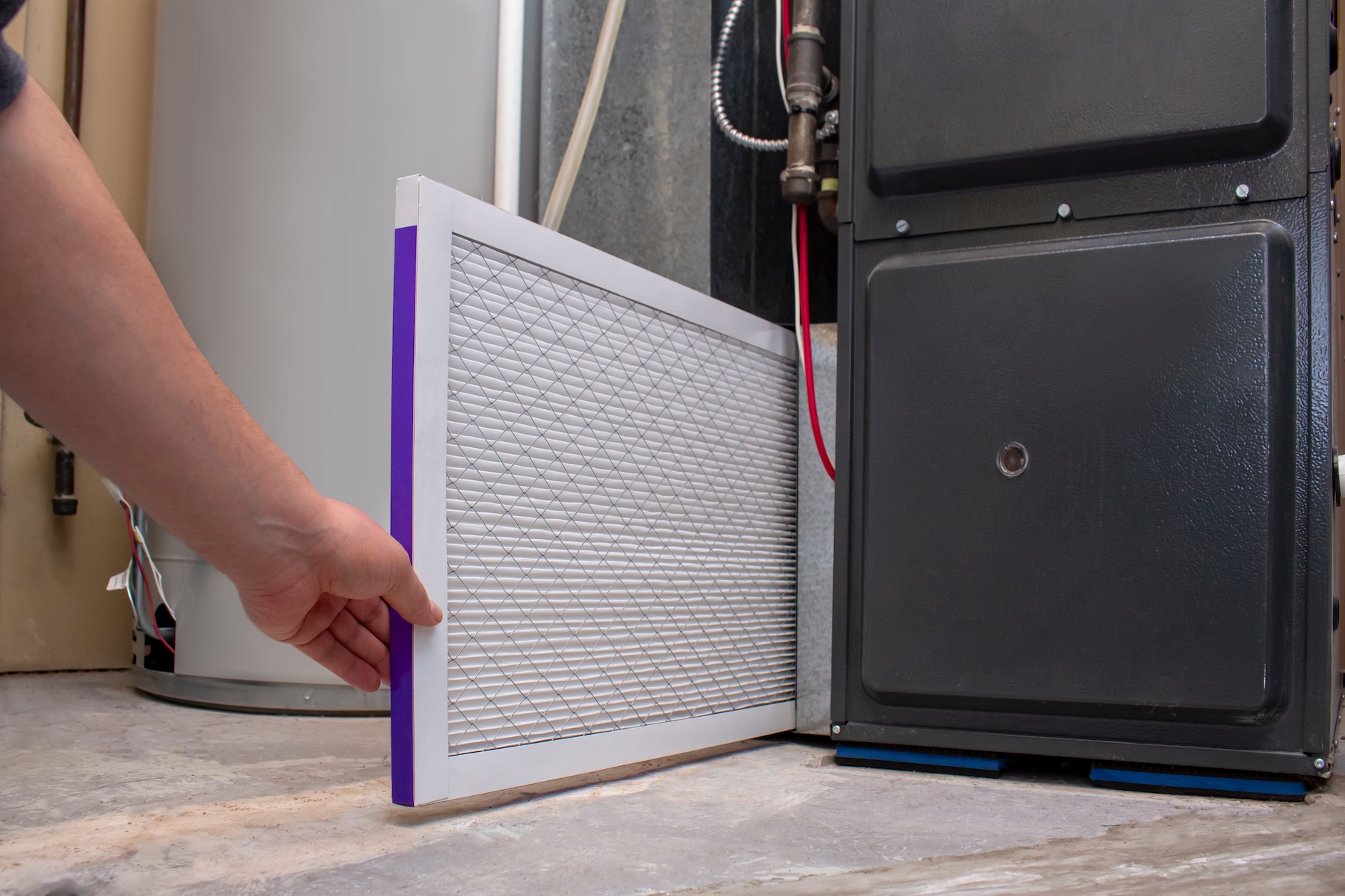 Person changing air filter in furnace unit.