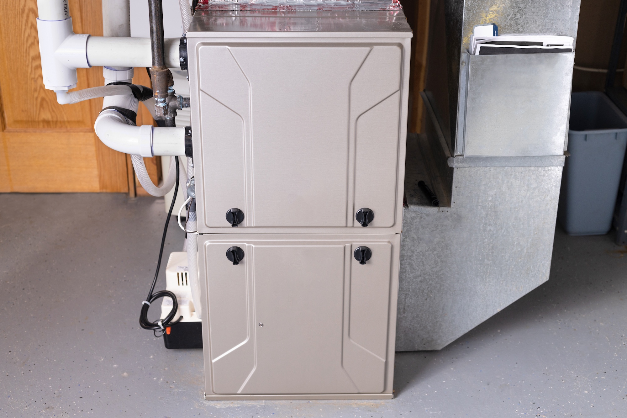 Modern home furnace with ductwork and piping in a utility room.