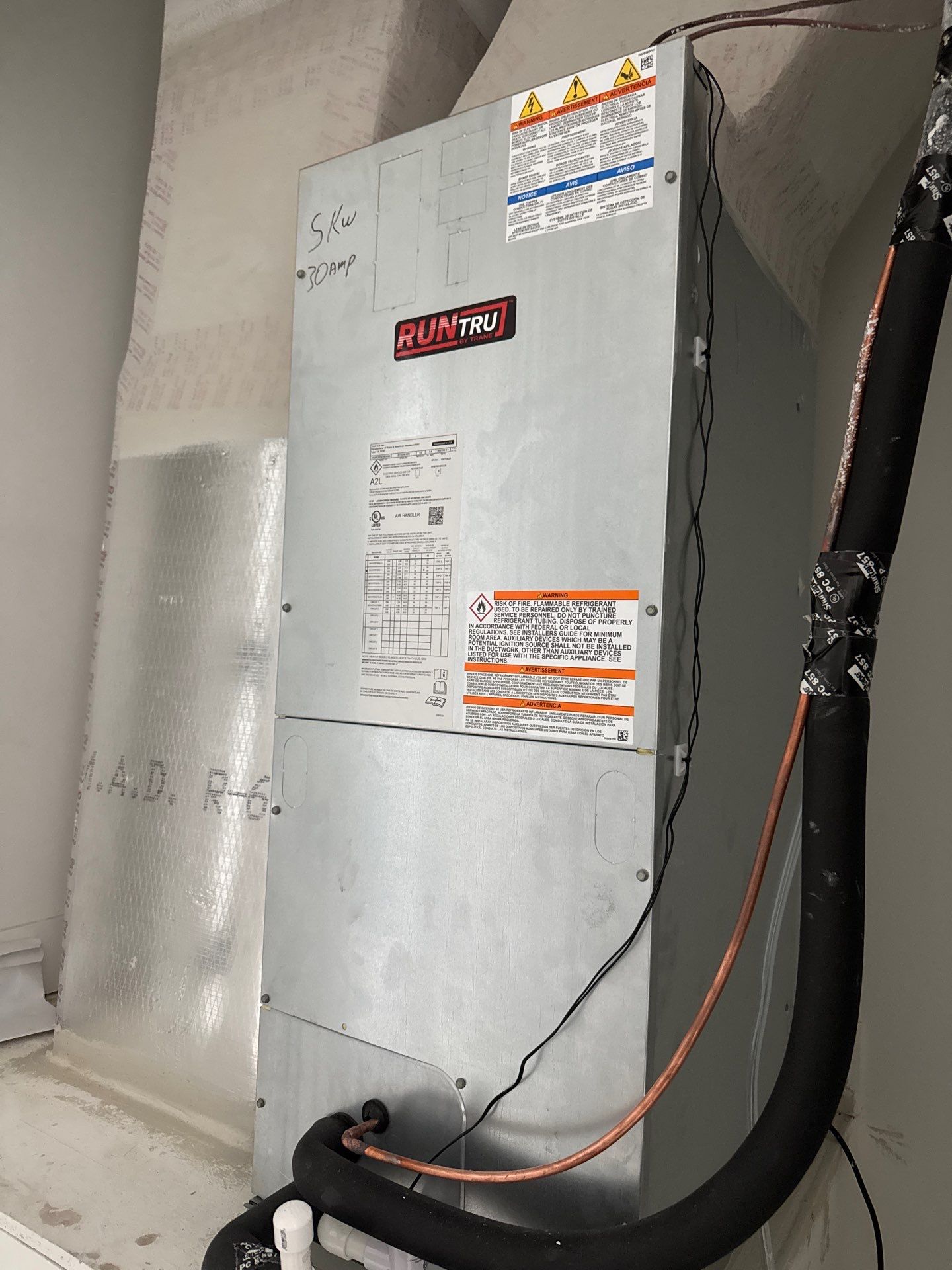 RUNTRU HVAC unit, silver, with copper piping and warning labels in a utility room.