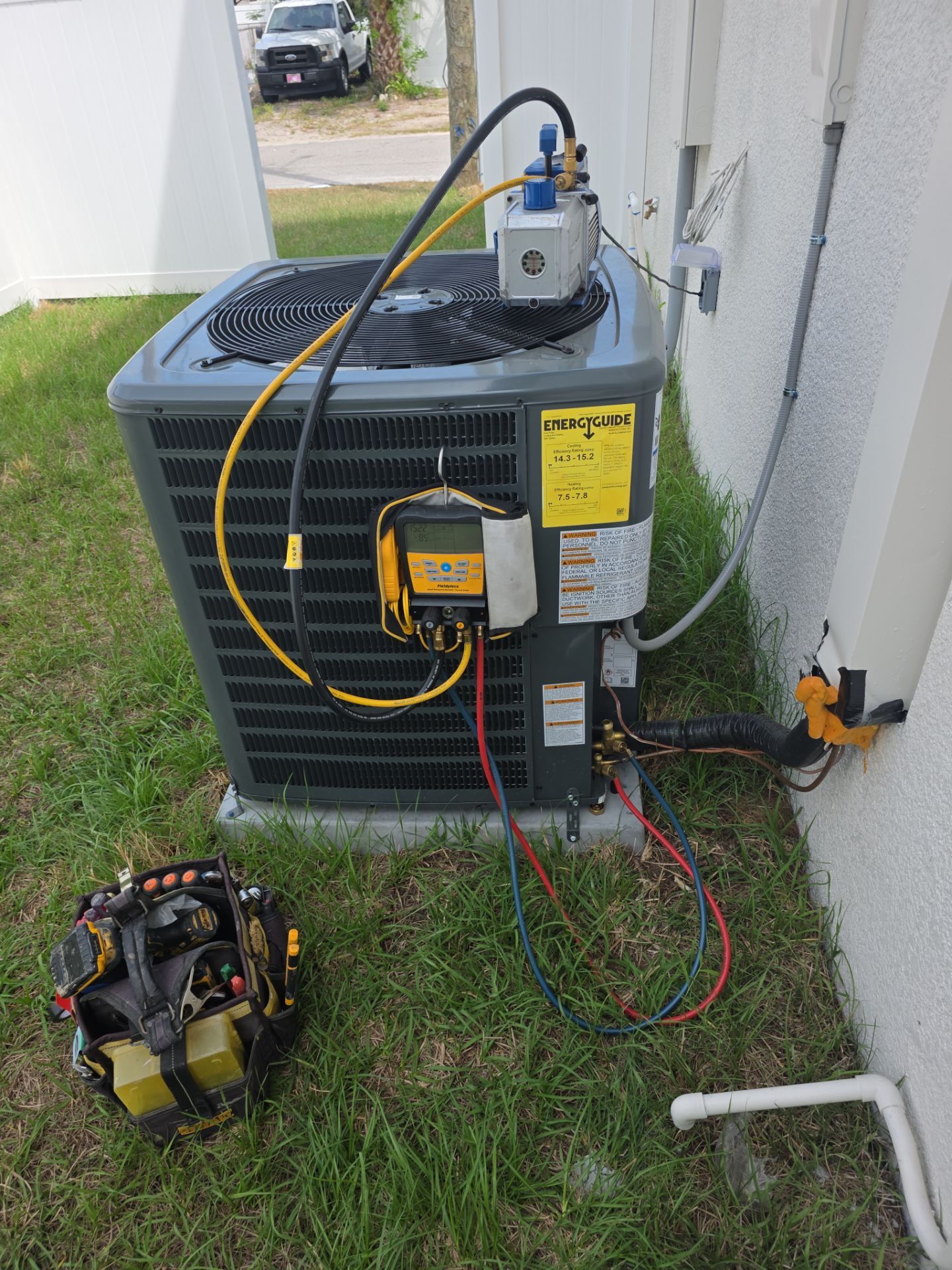 HVAC unit repair with tools on grass, wires connected, EnergyGuide label visible.