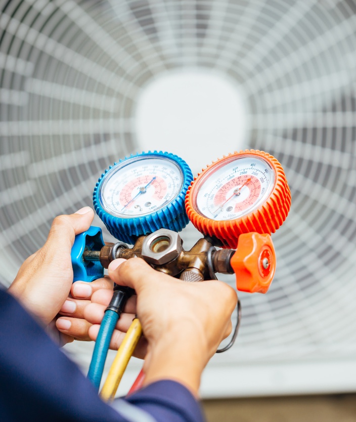 Technician using HVAC manifold gauge to check air conditioning system.
