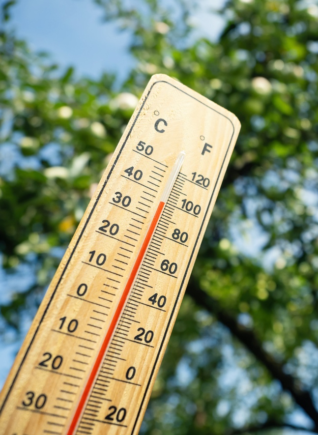 Wooden thermometer showing high temperature on a sunny day outdoors.