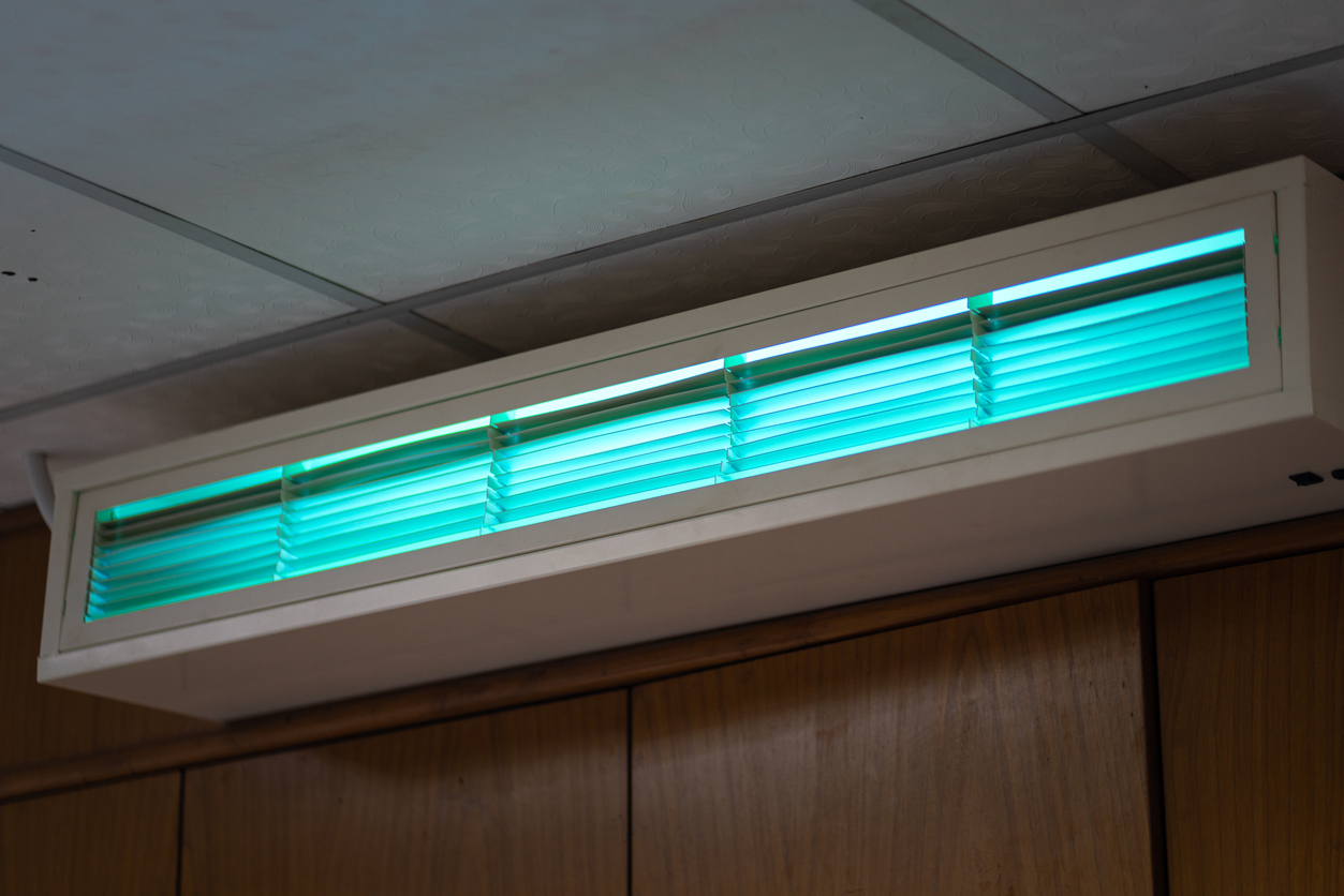 Wall-mounted air conditioning unit with glowing blue-green light.
