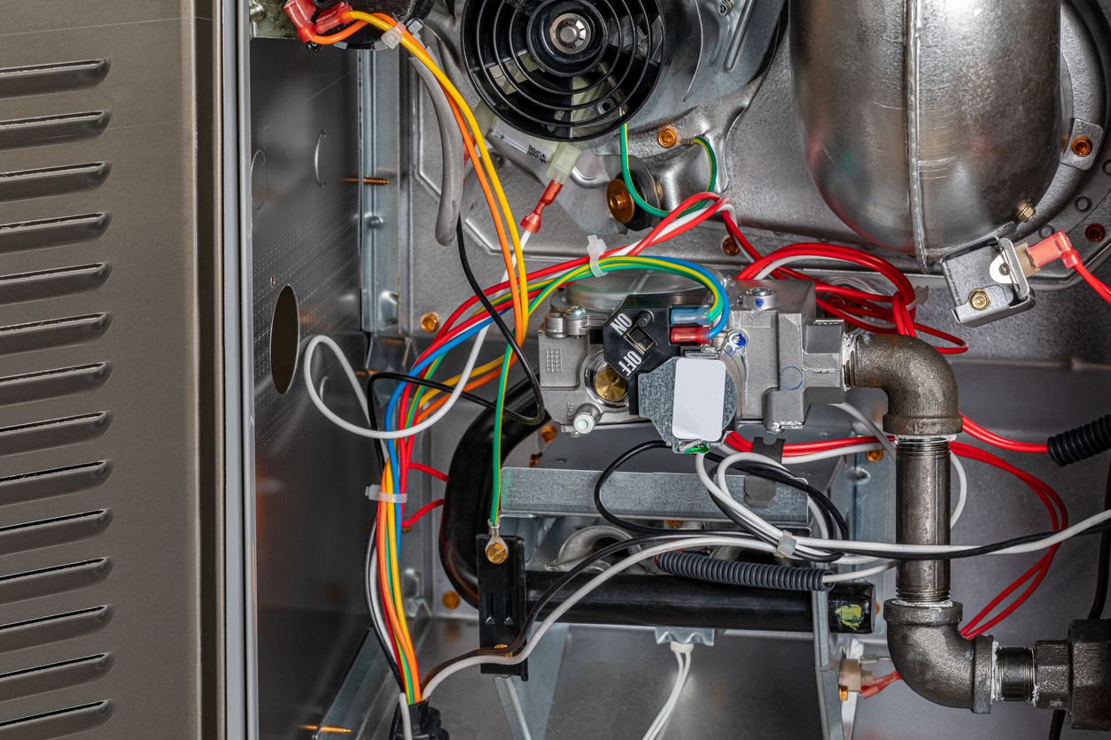 Close-up of a furnace with visible wires and components inside.