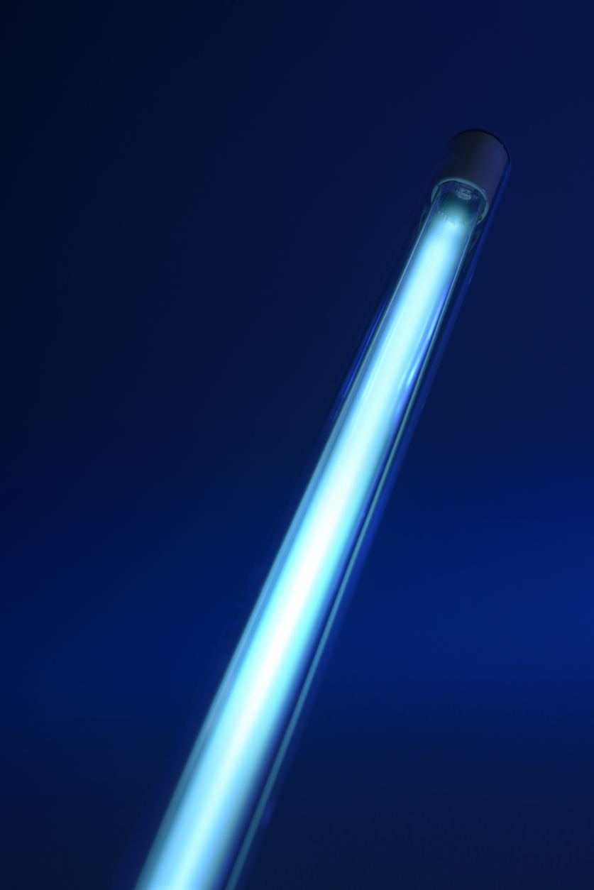 Close-up of a glowing blue fluorescent light tube against a dark blue background.
